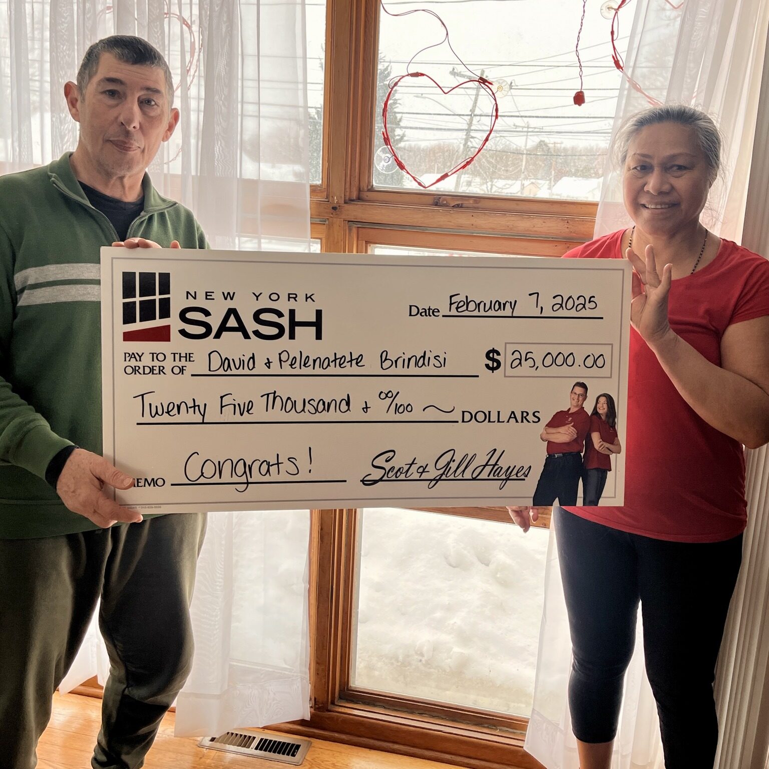 Excited New York Sash customers holding up a large check for $25,000, representing a major giveaway prize.