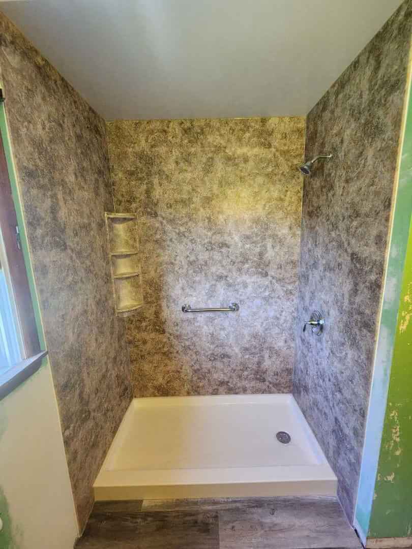 Completed walk-in shower with chrome fixtures and accessories.